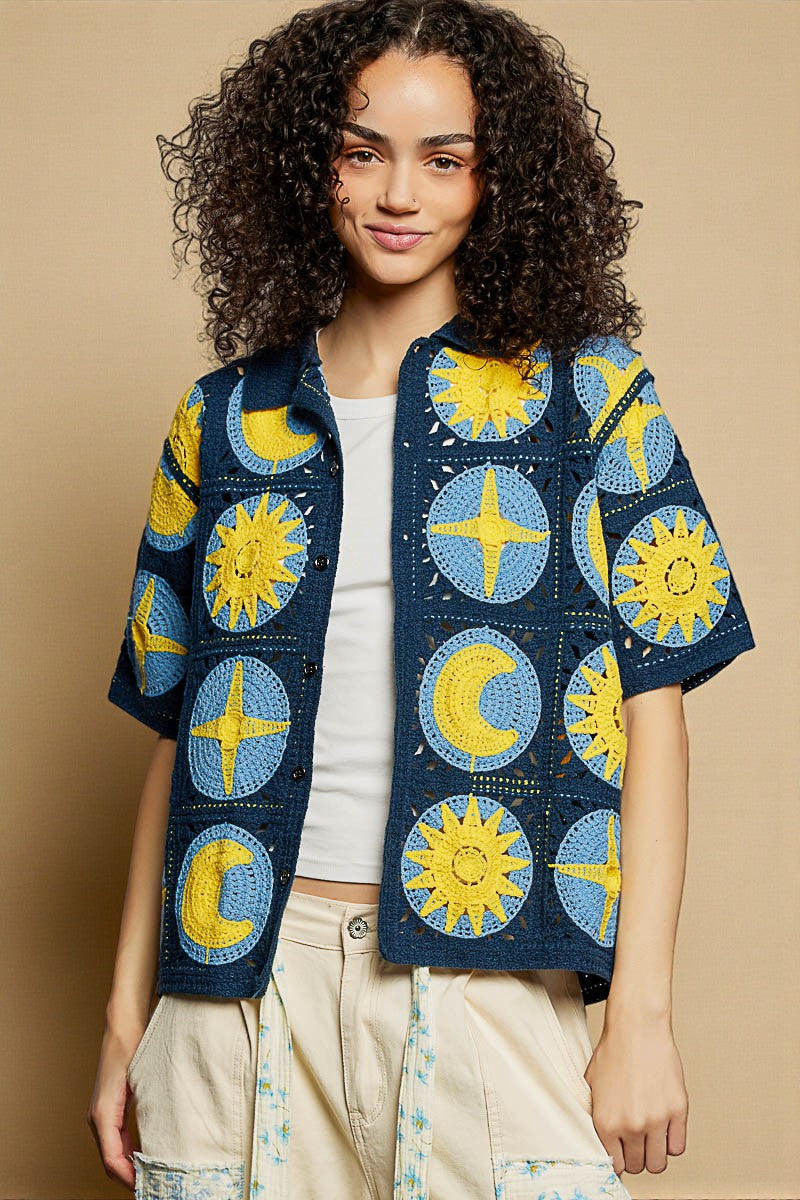 Woman wearing a colorful patterned jacket with sun and moon designs on a beige background