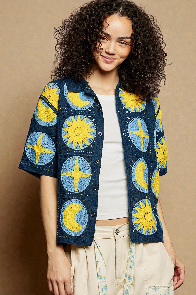 Woman wearing a colorful jacket with sun and moon patterns on a beige background