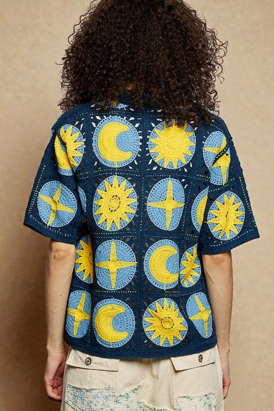 Person wearing a shirt with sun and moon pattern on a beige background
