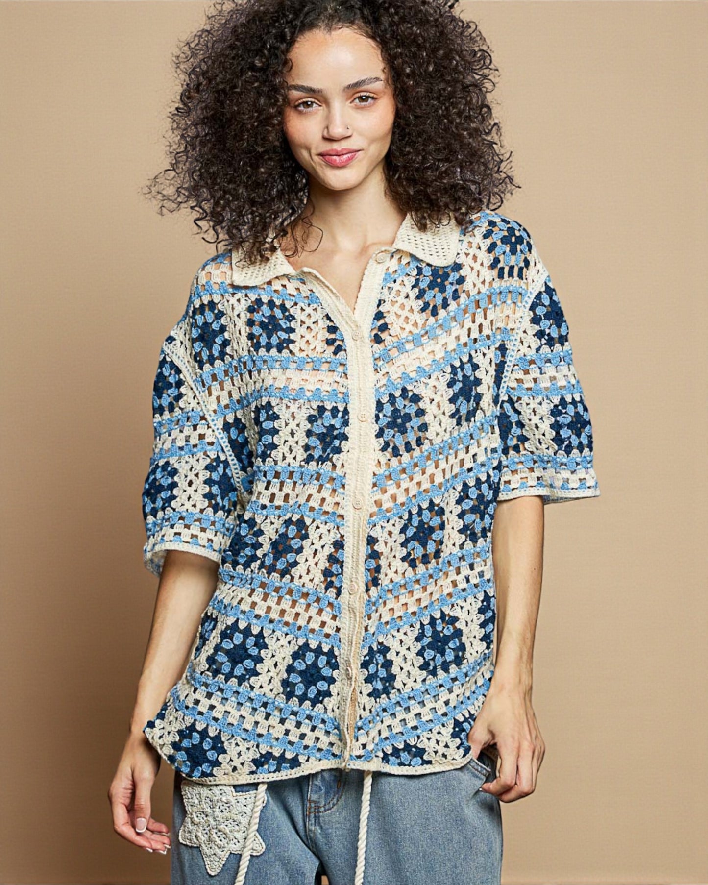 Woman wearing a colorful crochet jacket against a beige background