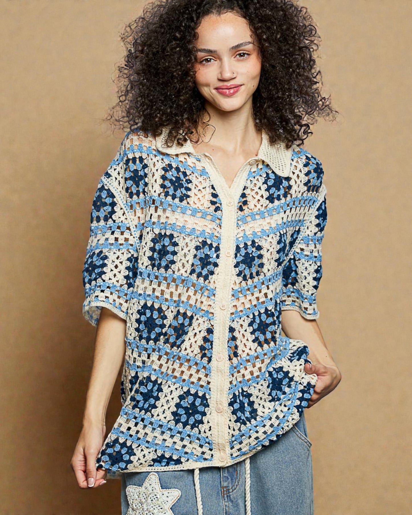 Woman wearing a blue and white patterned crochet shirt against a beige background