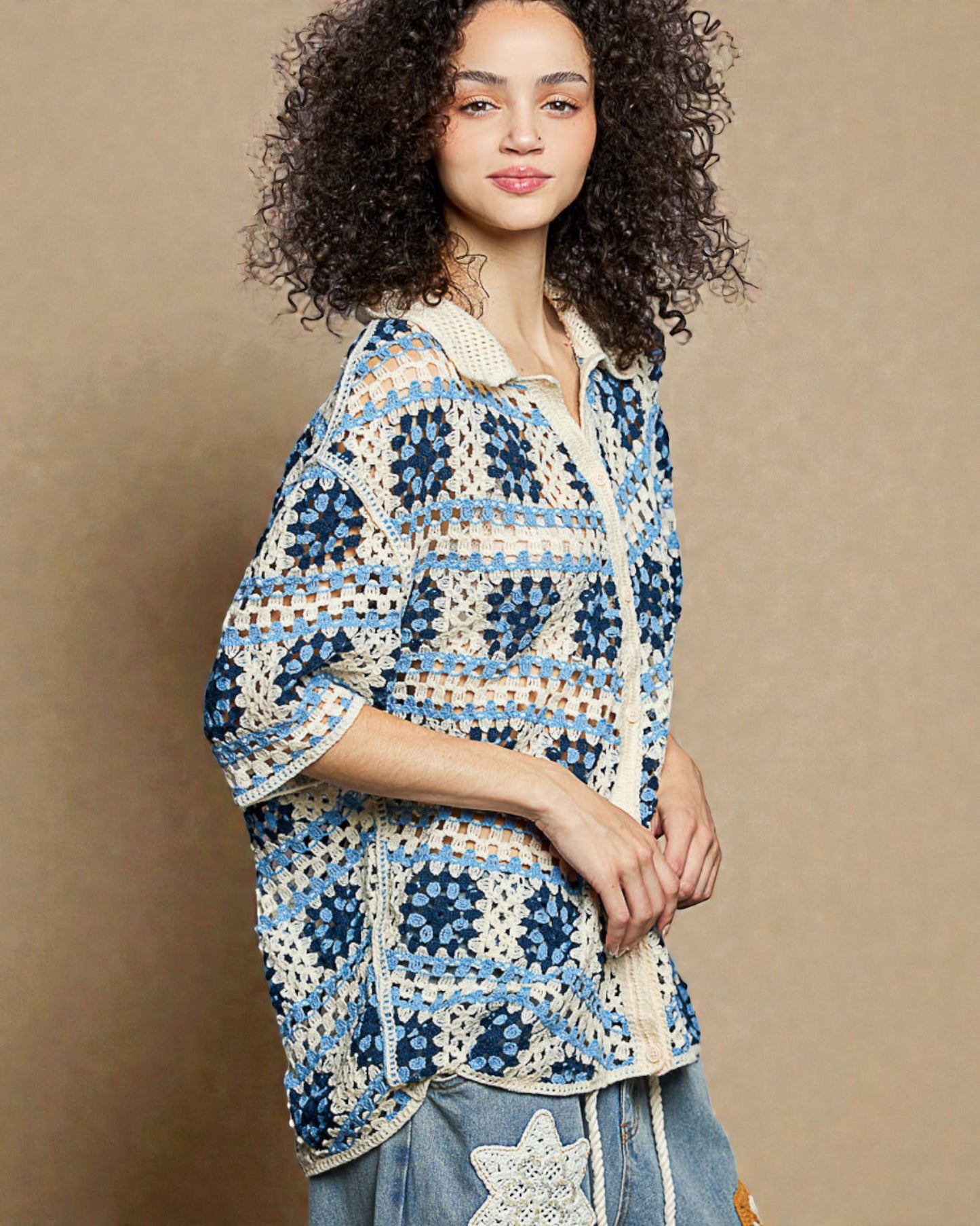 Woman wearing a blue and white patterned crochet top against a beige background