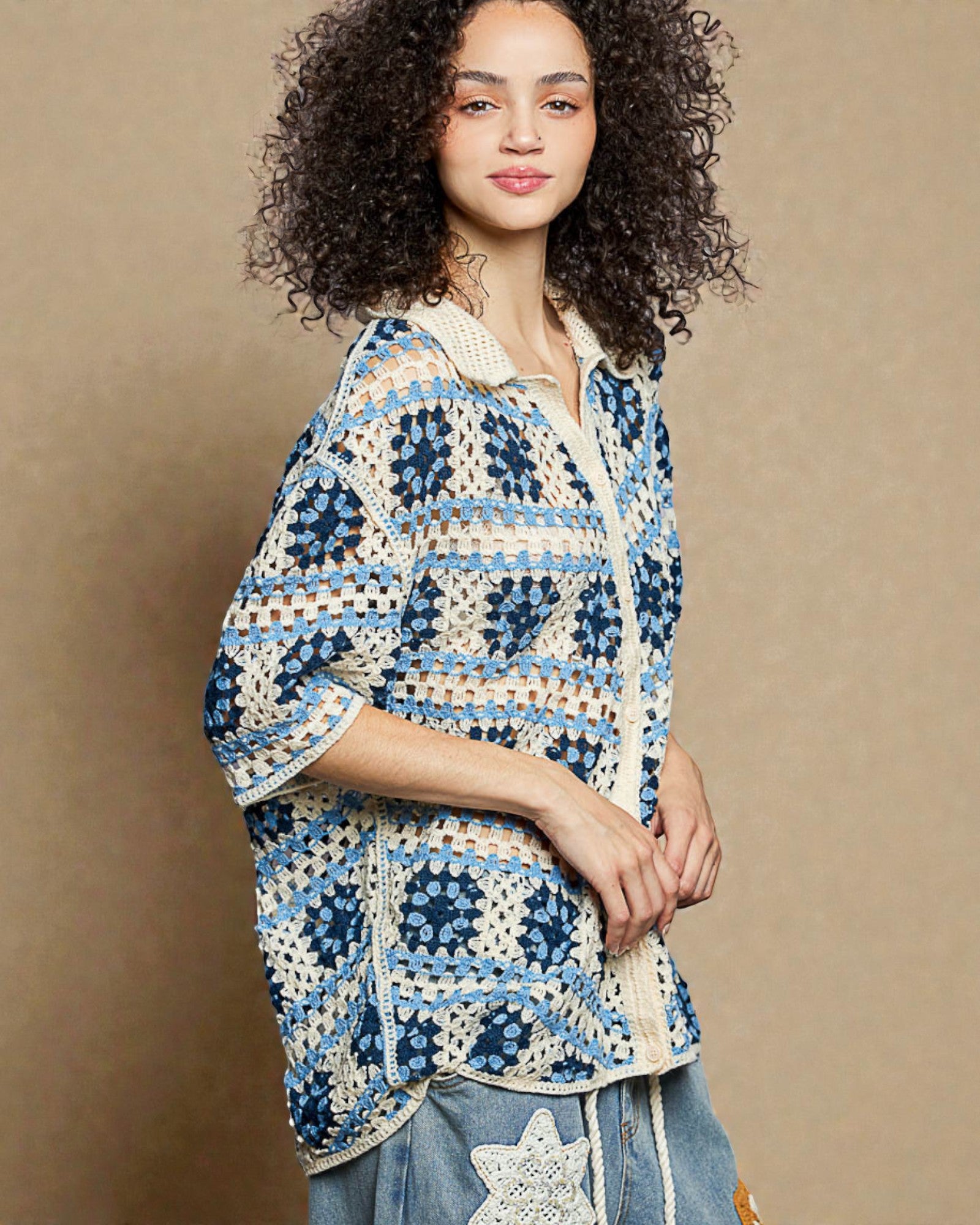 Woman wearing a blue and white patterned crochet top against a beige background
