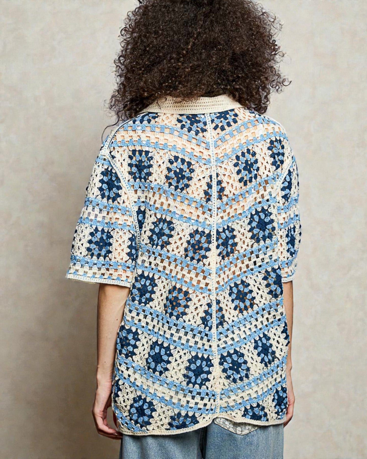 Person wearing a blue and white patterned shirt against a beige background