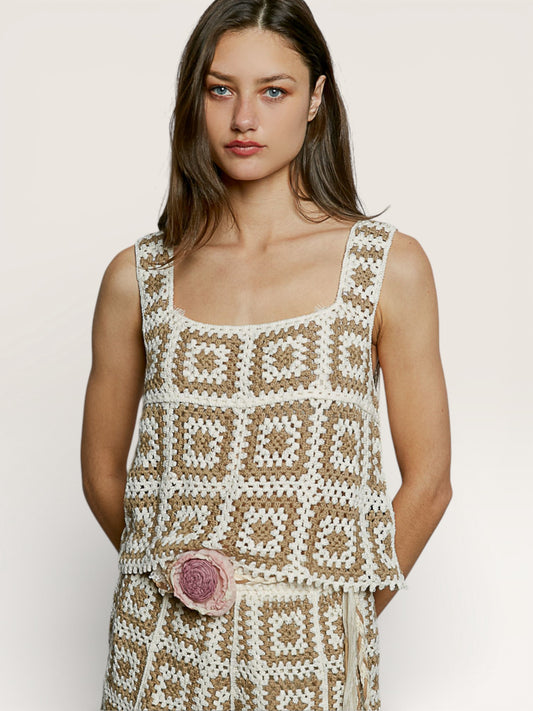 Woman wearing a patterned dress with a pink flower detail on a plain background