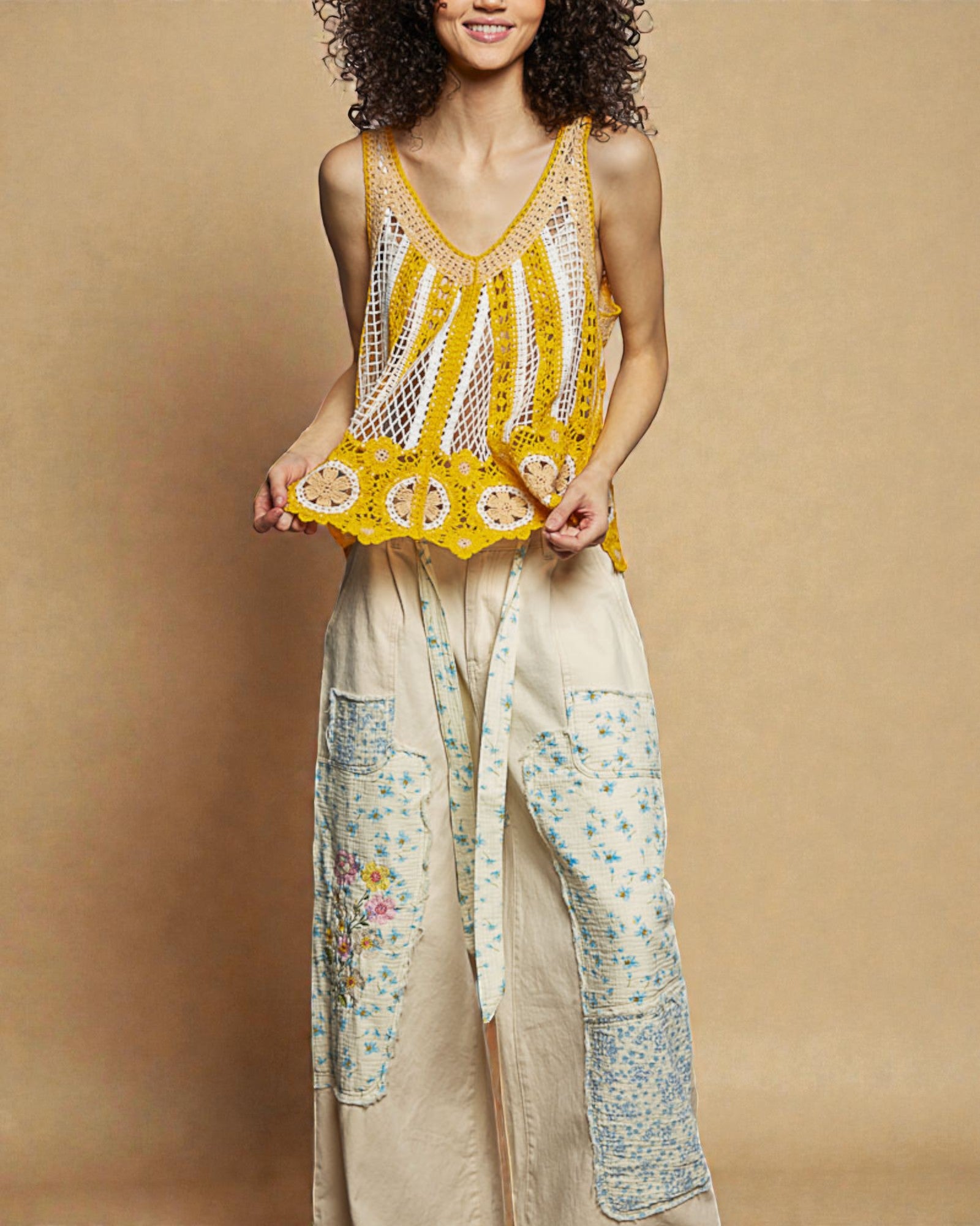 Woman wearing a yellow crochet top and floral skirt against a beige background