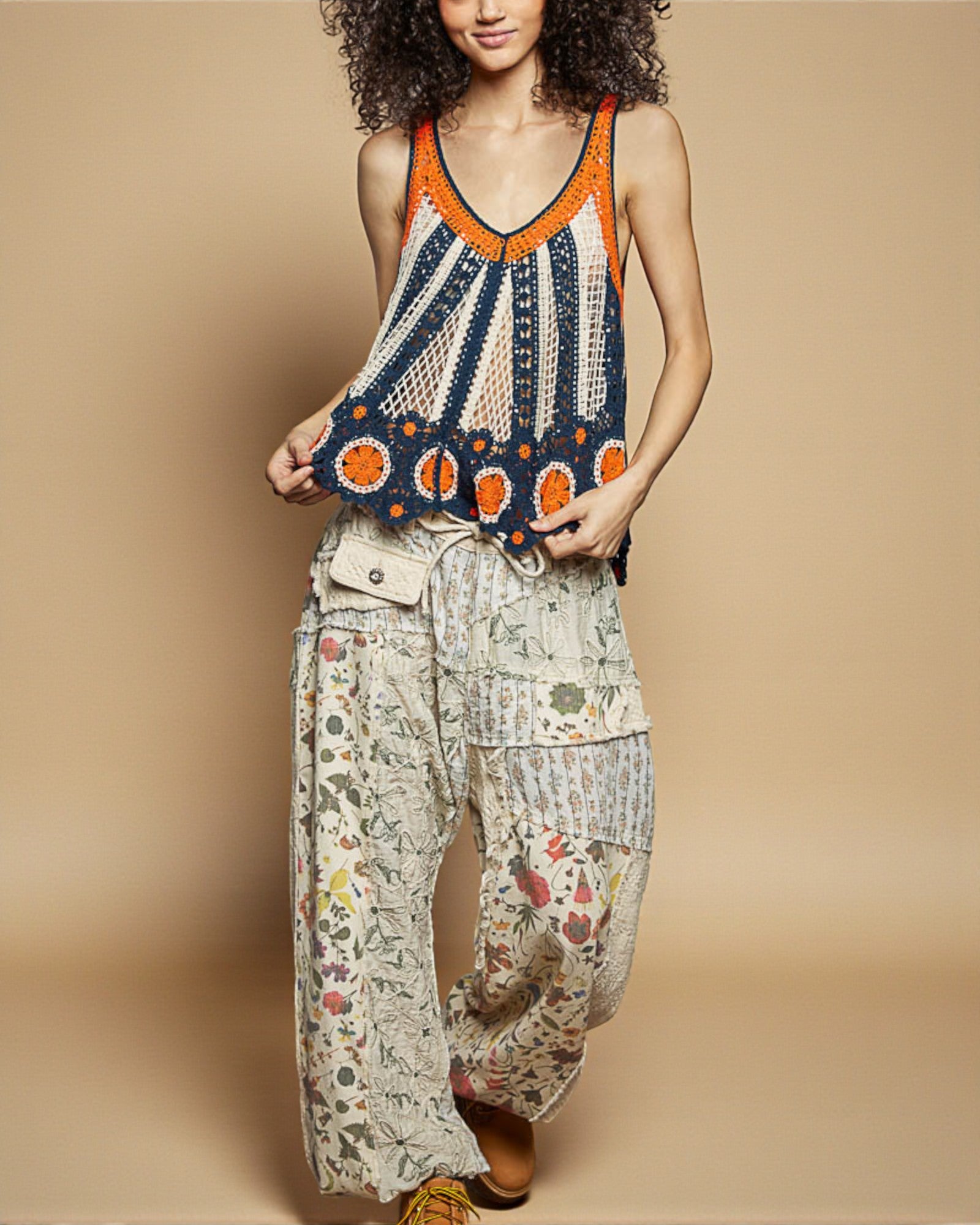 Woman wearing a colorful crochet top and patterned pants on a beige background