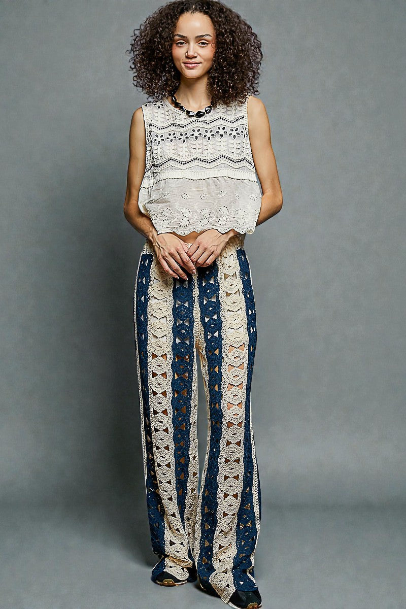 Woman wearing a sleeveless top and long pants with lace details against a gray background