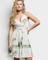 Woman wearing a white dress with green palm tree patterns on a plain background