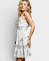 Woman wearing a white dress with green patterns on a light gray background