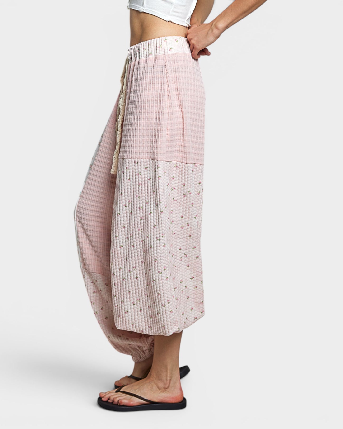 Person wearing a pink checkered pants with white patterns on a white background