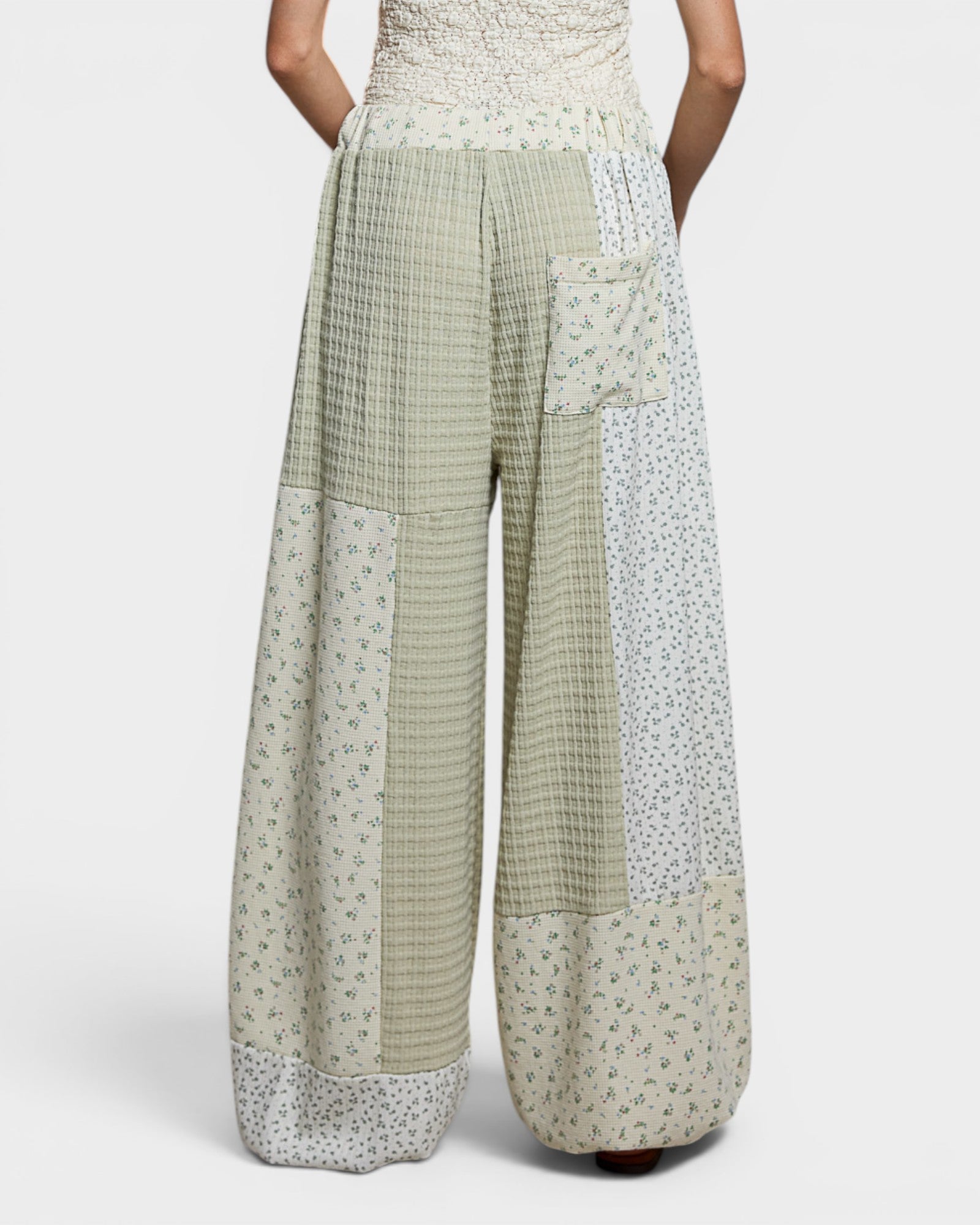 Person wearing a patterned outfit with wide-leg pants on a white background