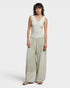 Woman wearing a sleeveless top and wide-leg pants with a white background