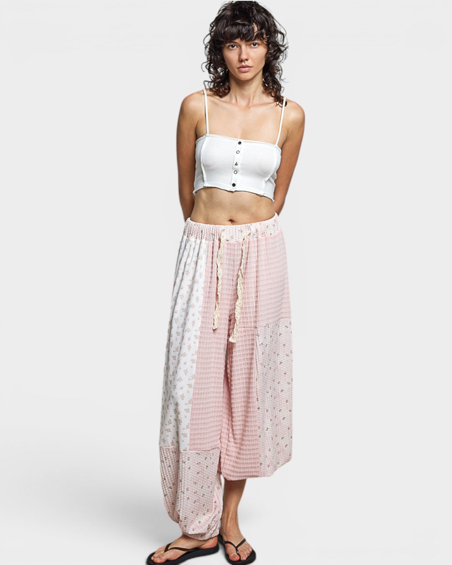 Woman wearing a white top and pants on a plain background