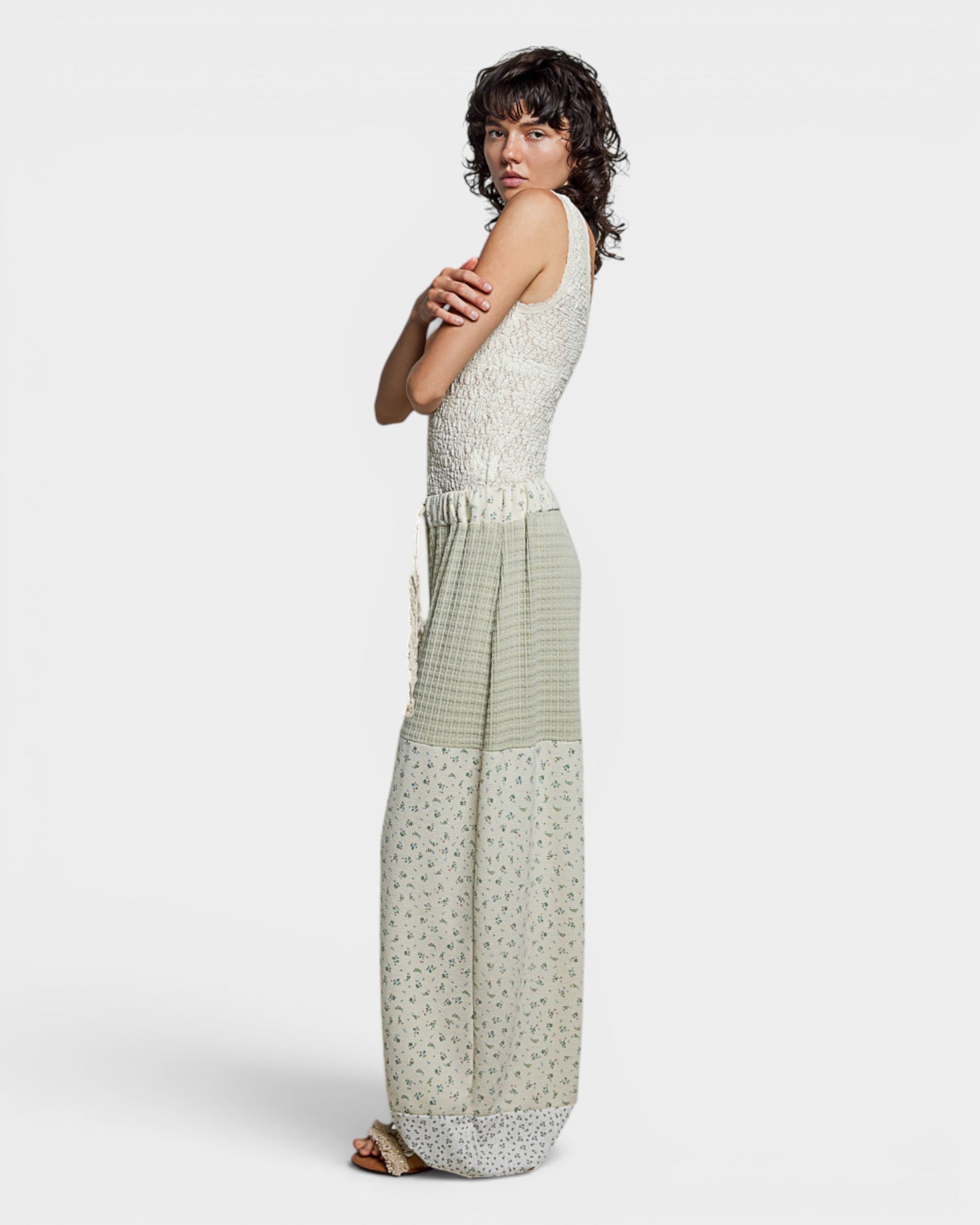 Woman wearing a sleeveless top and long pants with a white background