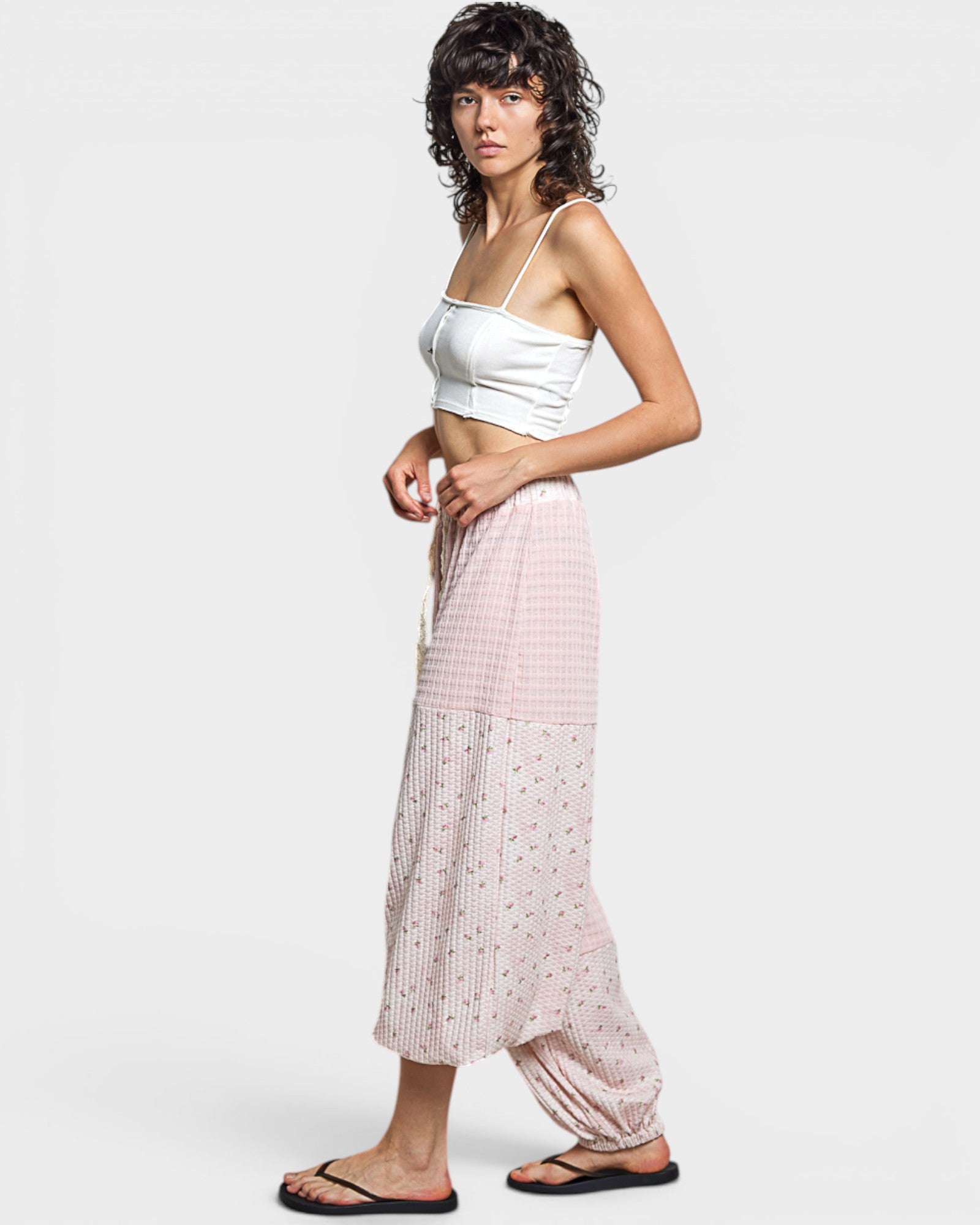 Woman wearing a white top and pink checkered pants on a plain background