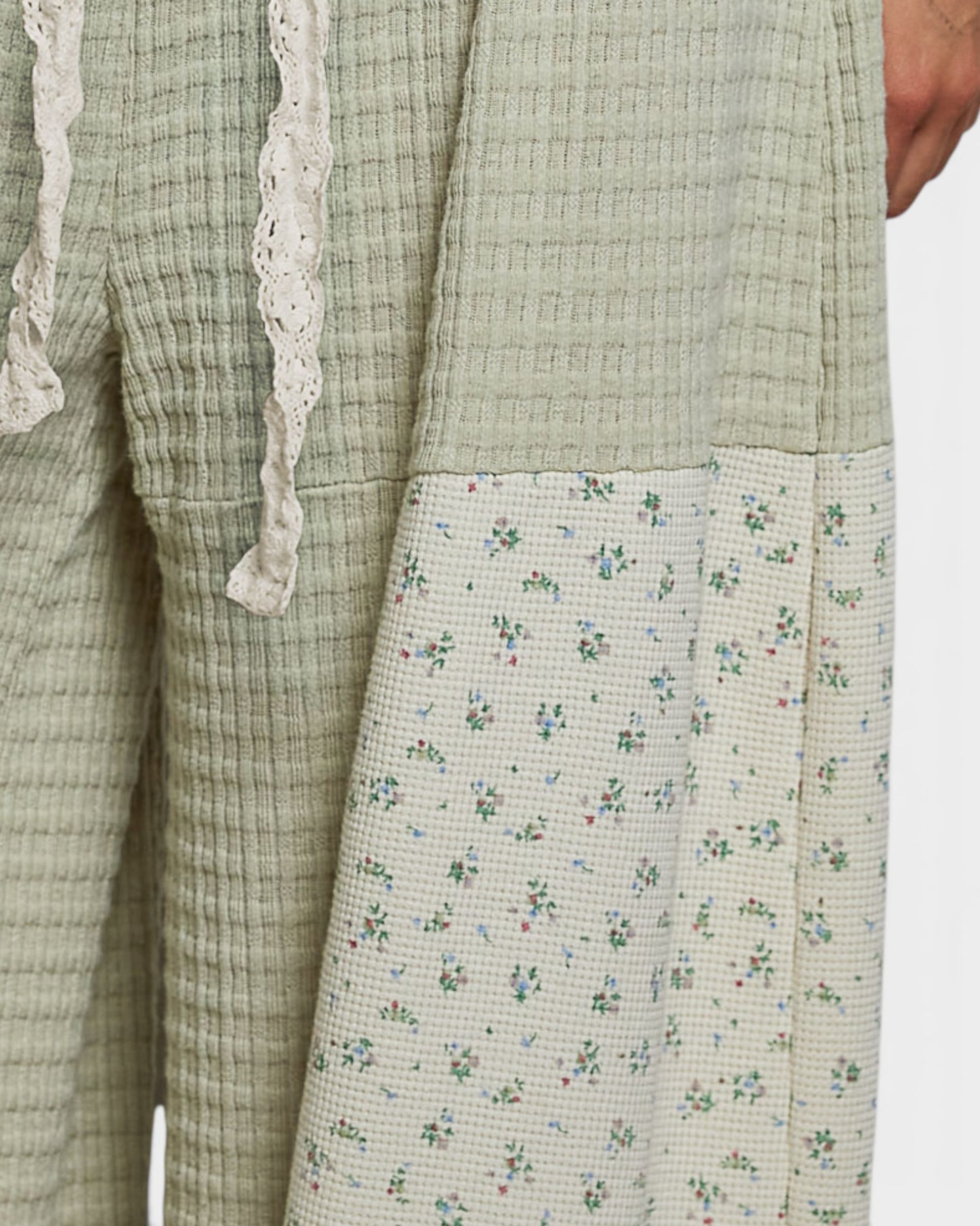 Light green checkered garment with floral patterned section on a white background