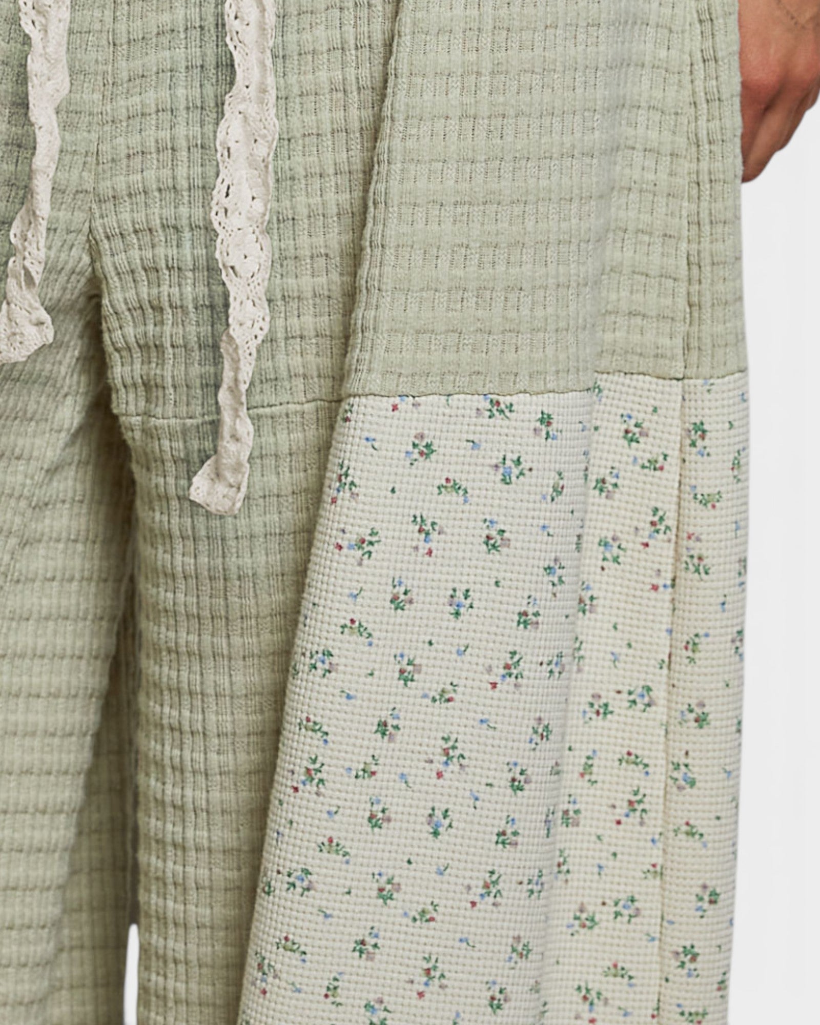 Light green checkered garment with floral patterned section on a white background