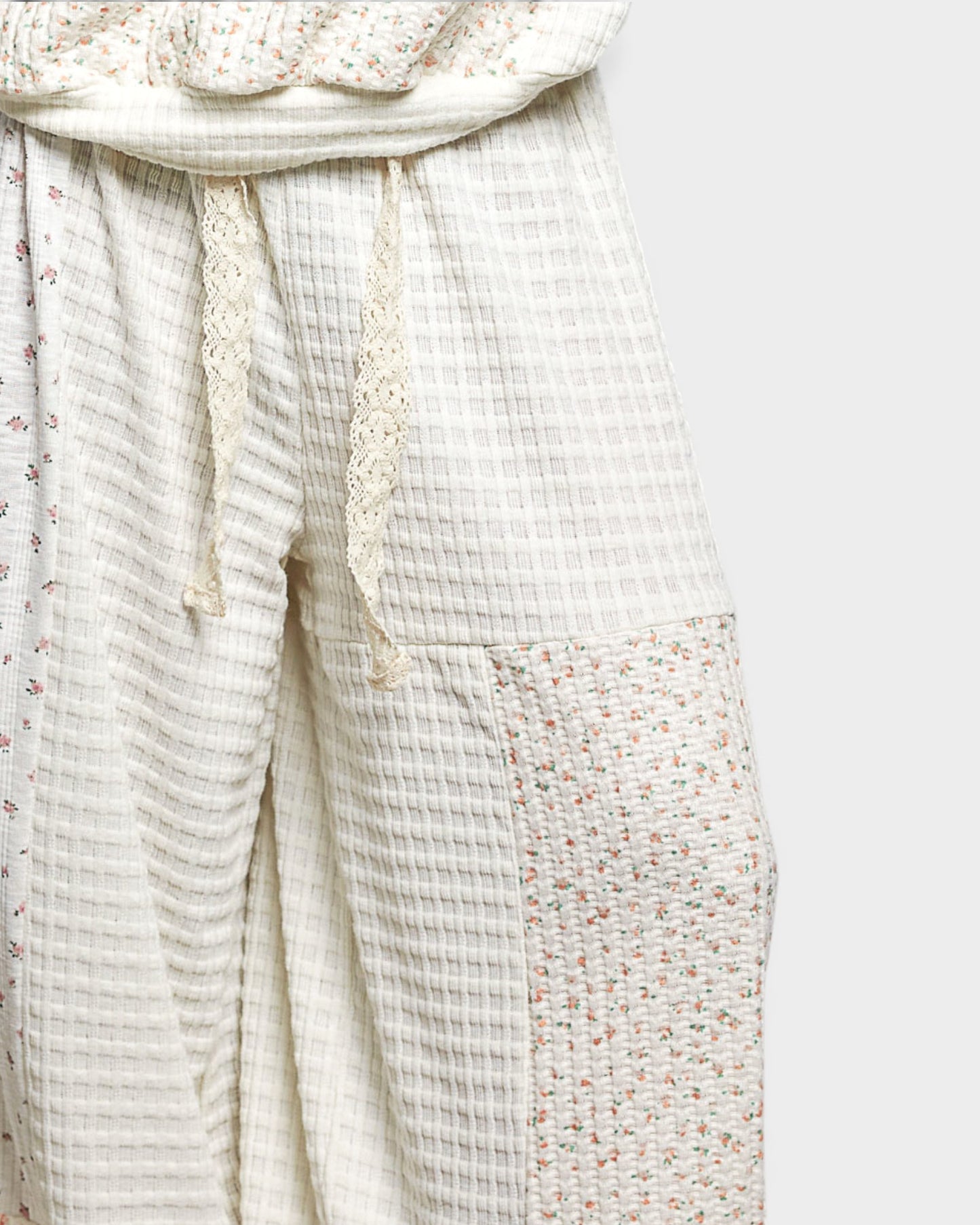 Light-colored textured fabric with floral trim on a white background