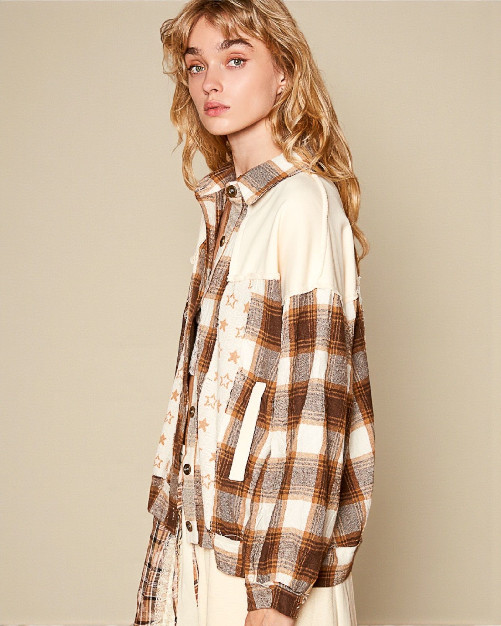 Woman wearing a plaid shirt over a white top against a beige background