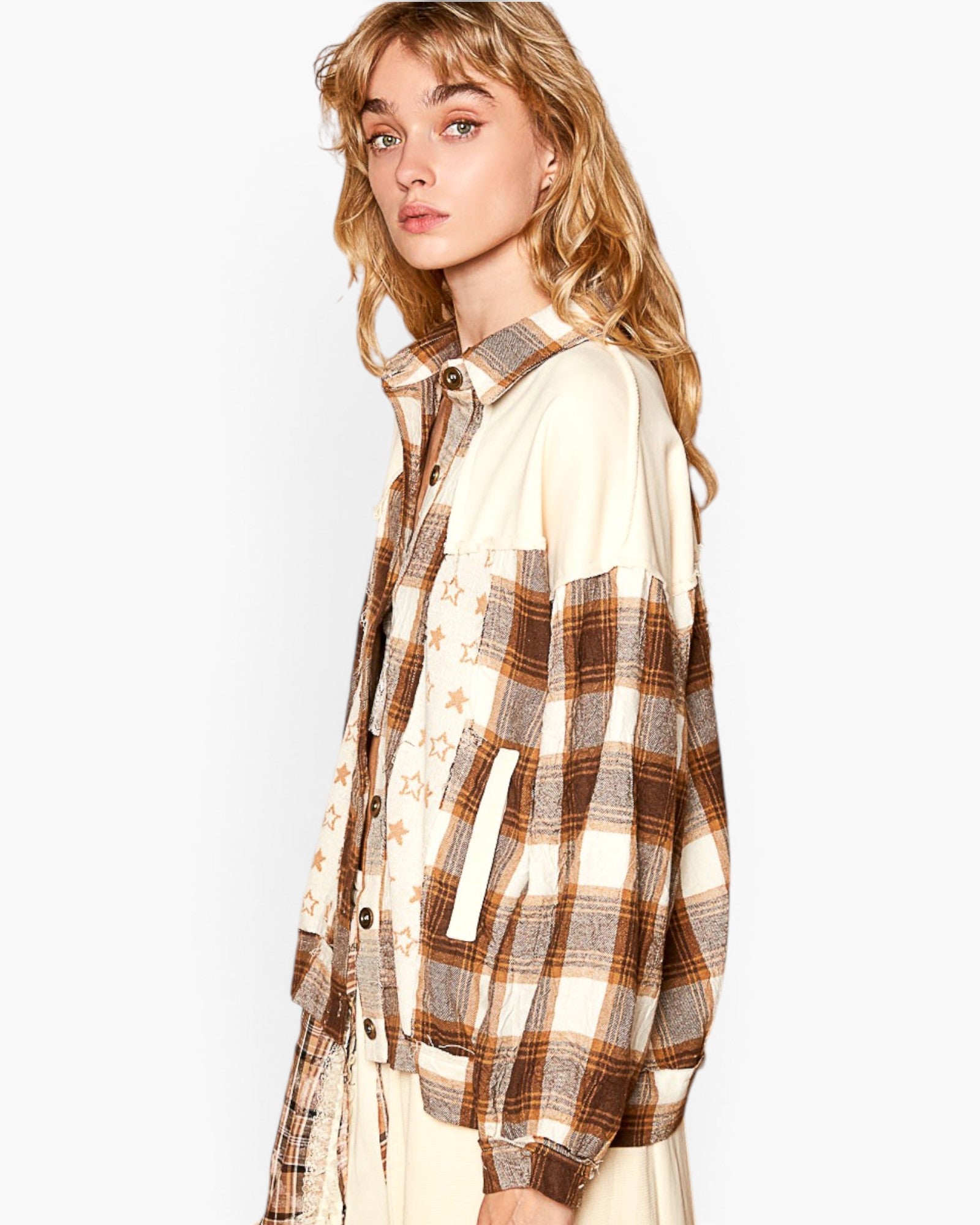 A woman wearing a mixed-media shirt jacket featuring a brown and beige plaid pattern on one side and a cream fabric with small gold star prints on the other, shown against a plain white background.