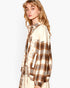 A woman wearing a mixed-media shirt jacket featuring a brown and beige plaid pattern on one side and a cream fabric with small gold star prints on the other, shown against a plain white background.