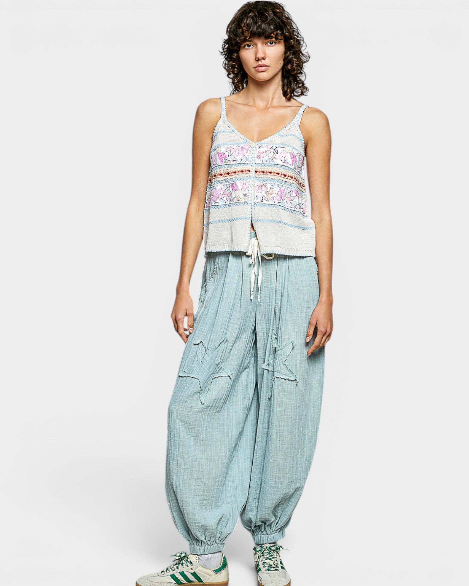 Woman wearing a floral top and light blue pants on a white background