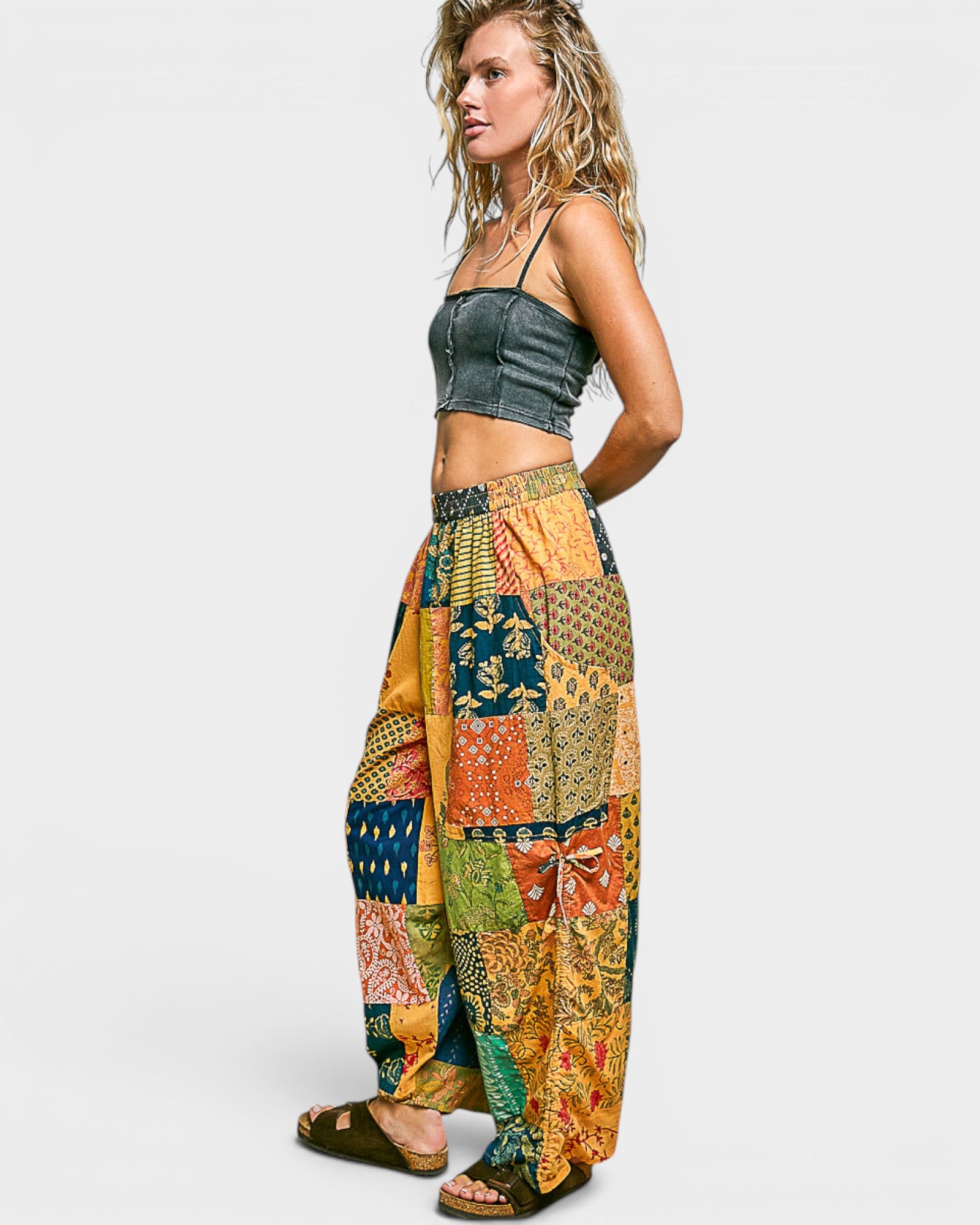 Woman wearing a colorful patchwork pants and denim crop top on a white background