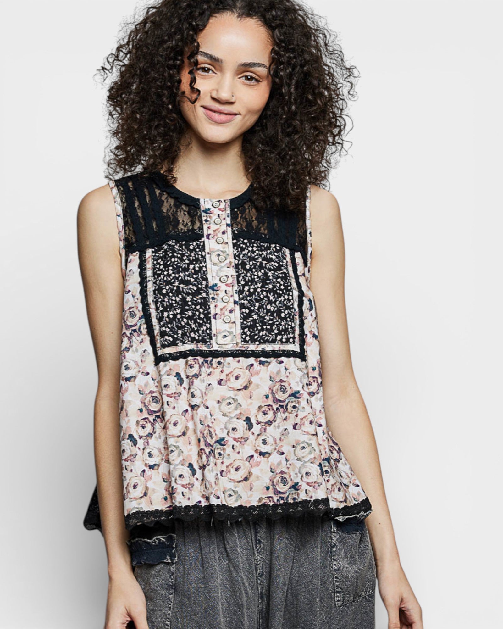 Woman wearing a sleeveless top with floral and lace patterns on a plain background