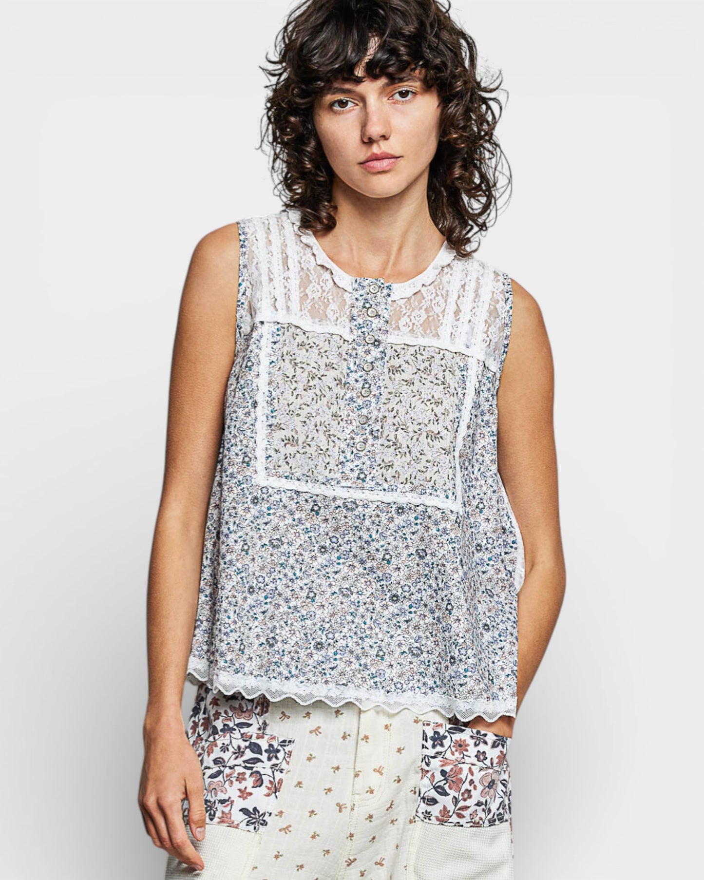 Woman wearing a sleeveless floral top against a plain background