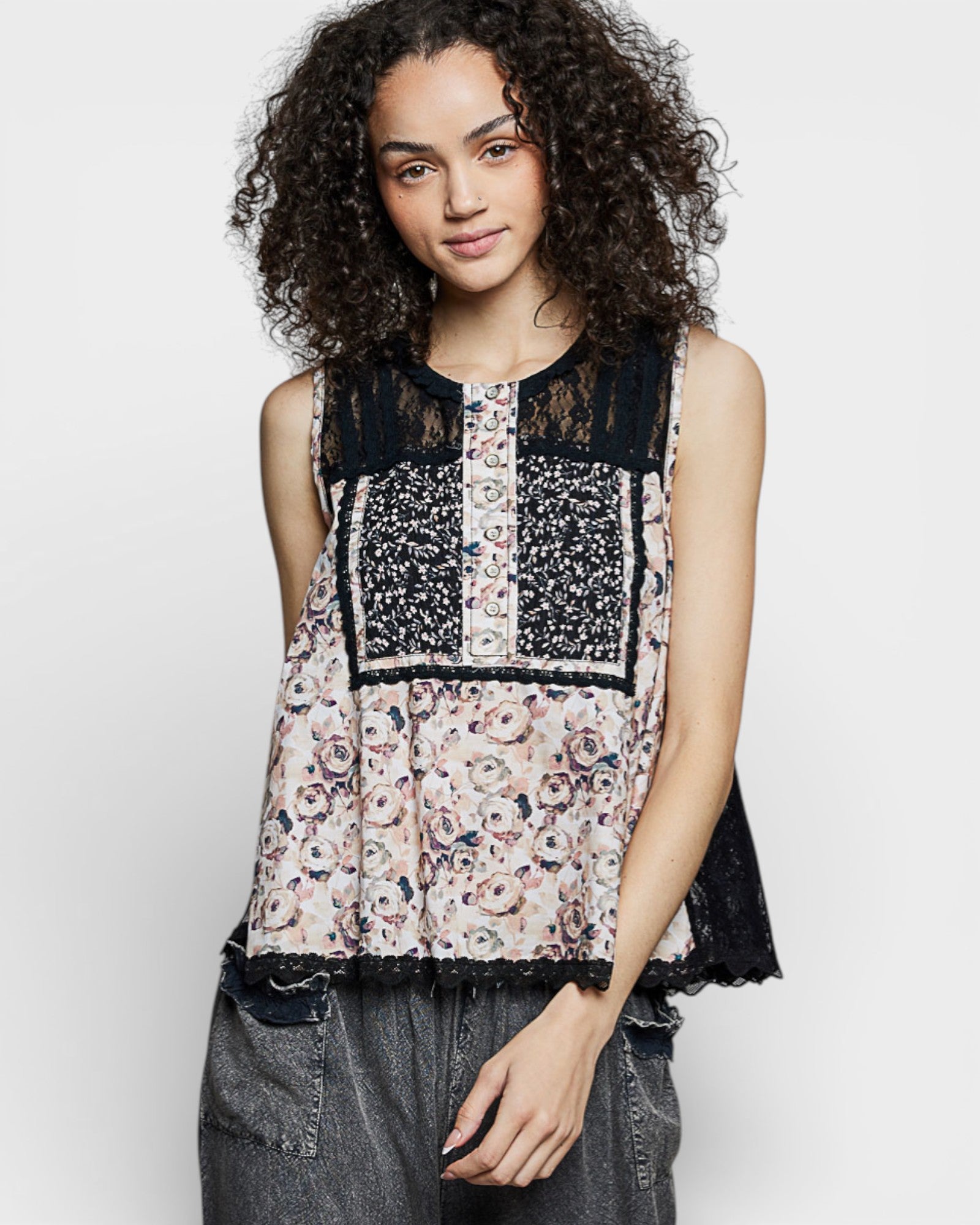 Woman wearing a sleeveless top with floral and lace patterns on a white background