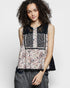 Woman wearing a sleeveless top with floral and lace patterns on a white background