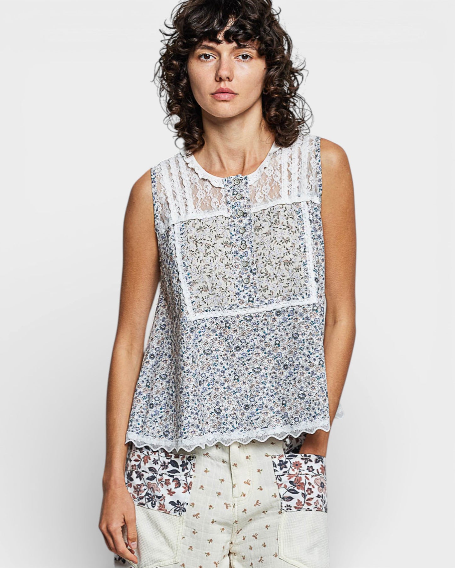 Woman wearing a sleeveless floral top with a plain background