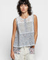 Woman wearing a sleeveless floral top with a plain background