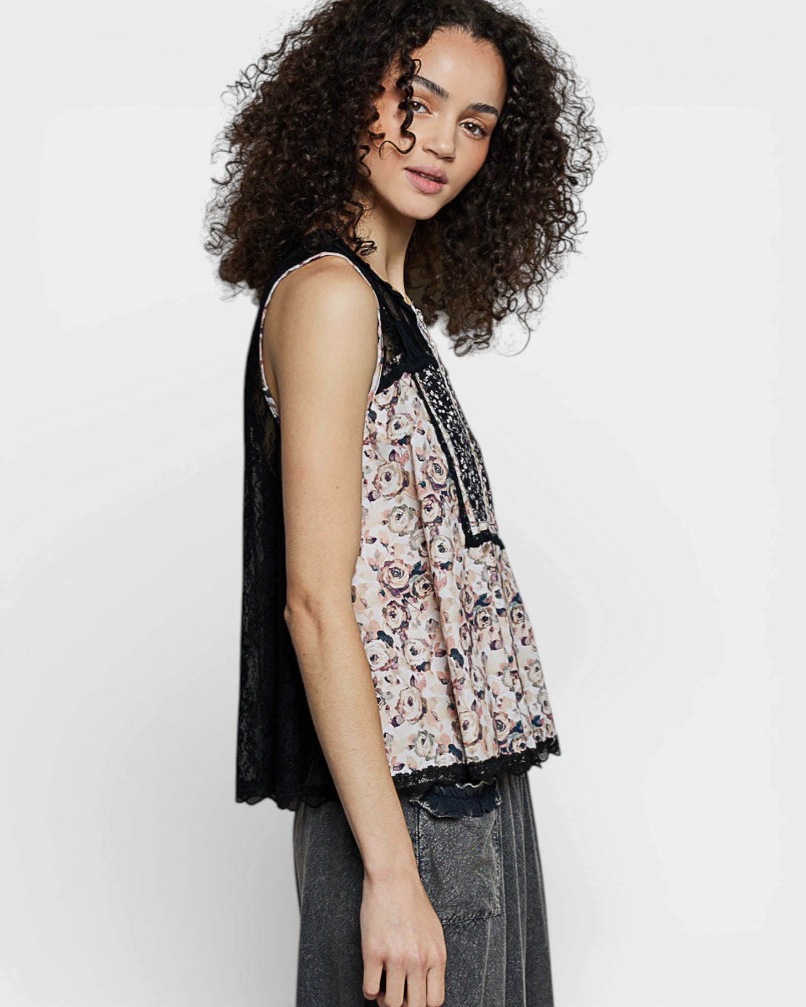 Woman wearing a floral sleeveless top with black accents on a white background