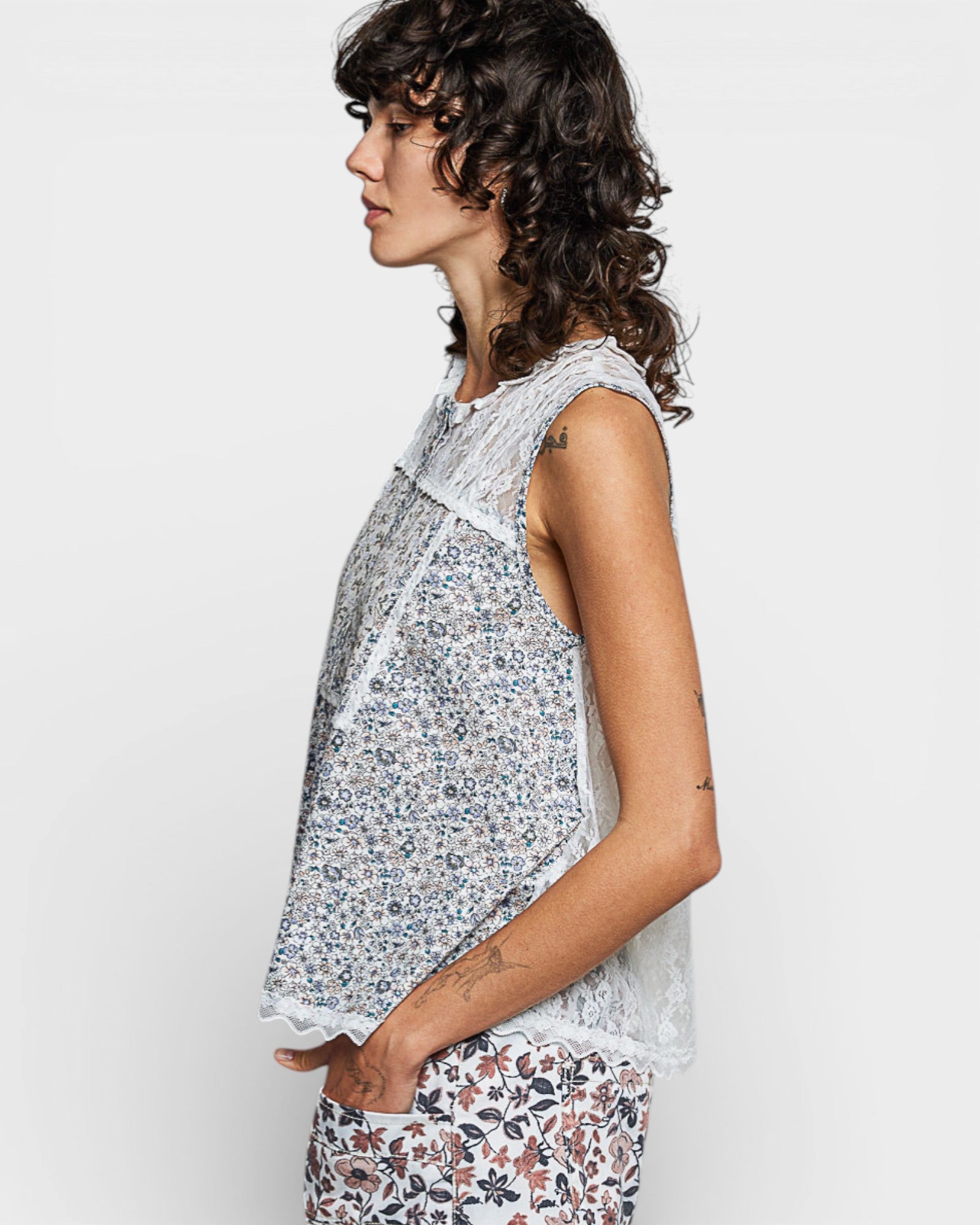 Woman wearing a floral sleeveless top and pants on a white background