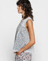 Woman wearing a floral sleeveless top and pants on a white background