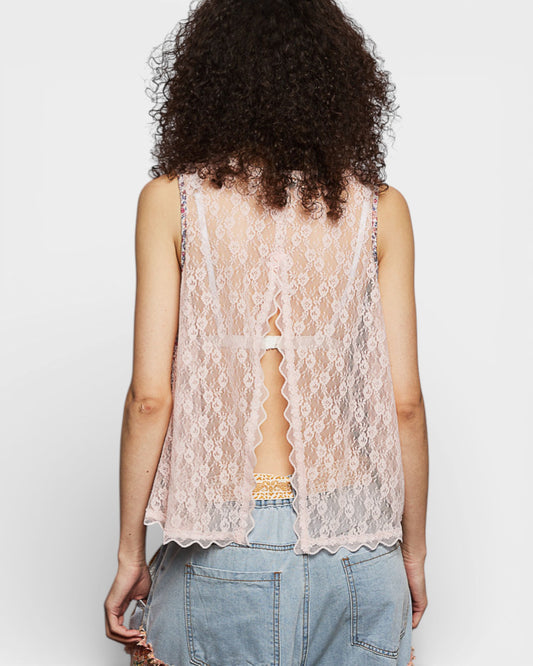 Person wearing a lace sleeveless top and denim shorts on a plain background