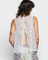 Person wearing a white lace top with floral pants on a plain background