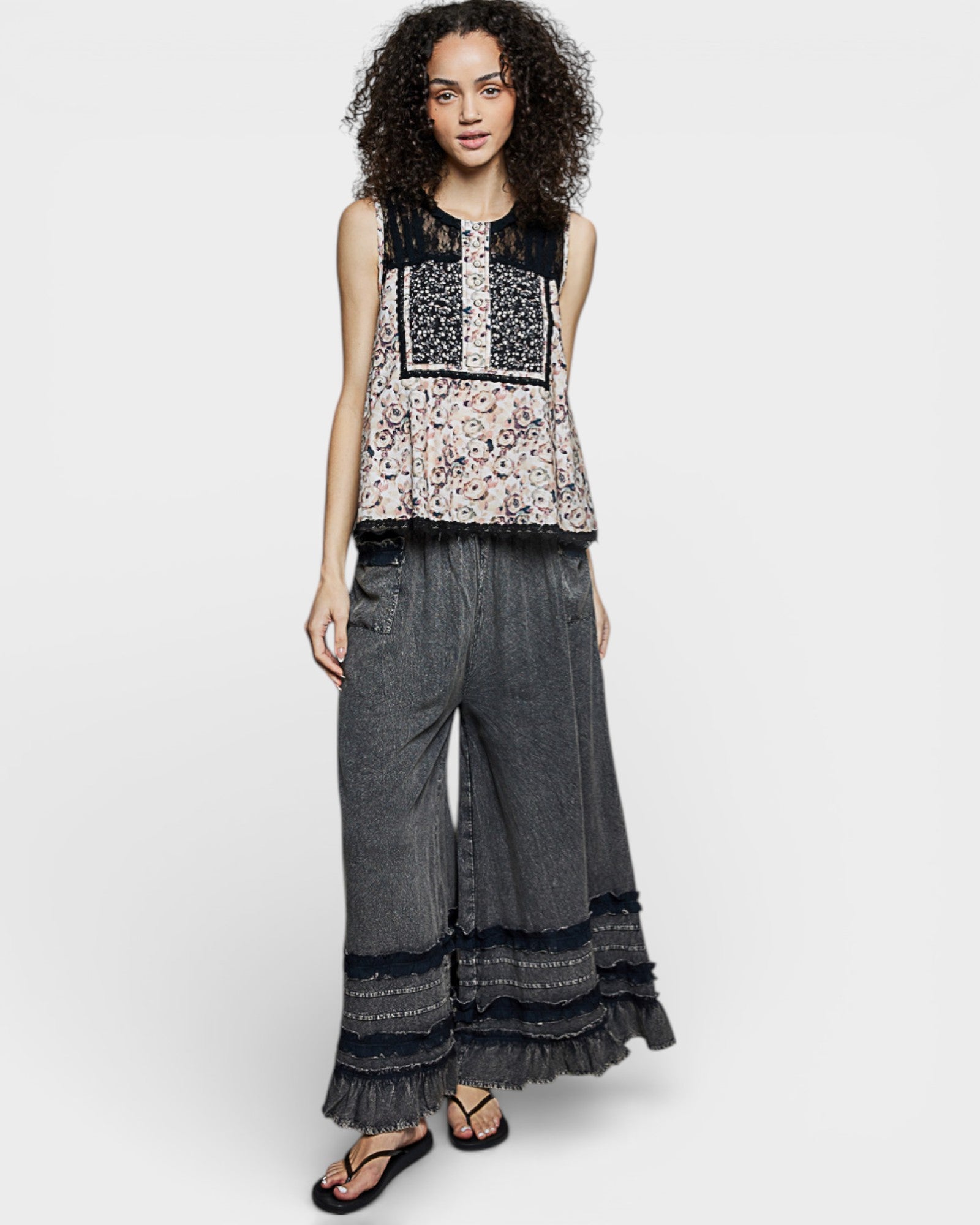 Woman wearing a patterned top and wide-leg pants on a white background