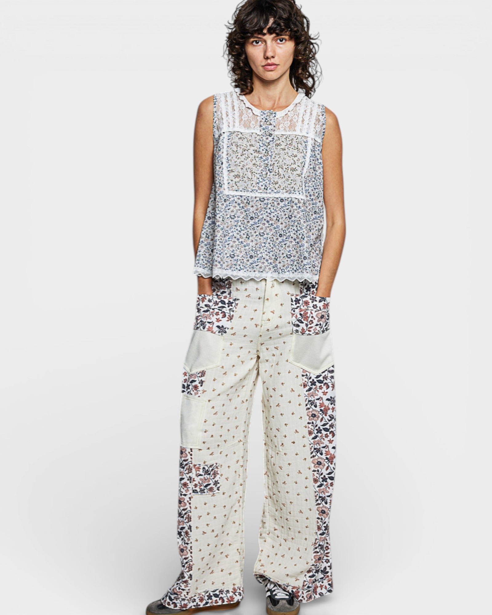 Person wearing a sleeveless top and wide-leg pants with floral patterns on a white background