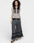Woman wearing a patterned top and wide-leg pants on a white background