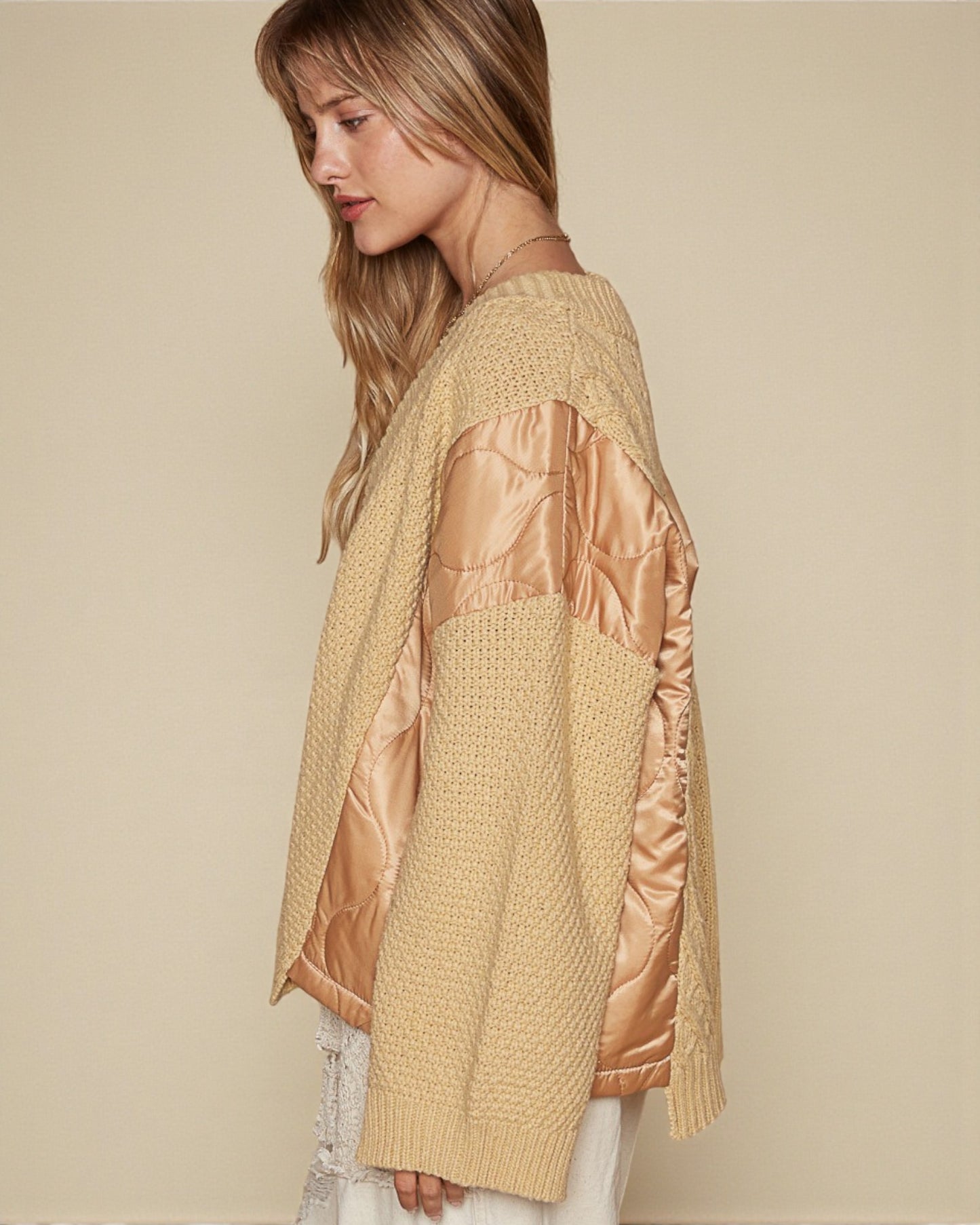 Woman wearing a beige and rose gold jacket against a beige background