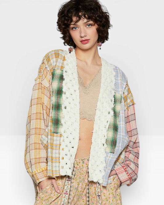 Woman wearing a colorful plaid jacket over a beige top and floral pants on a white background