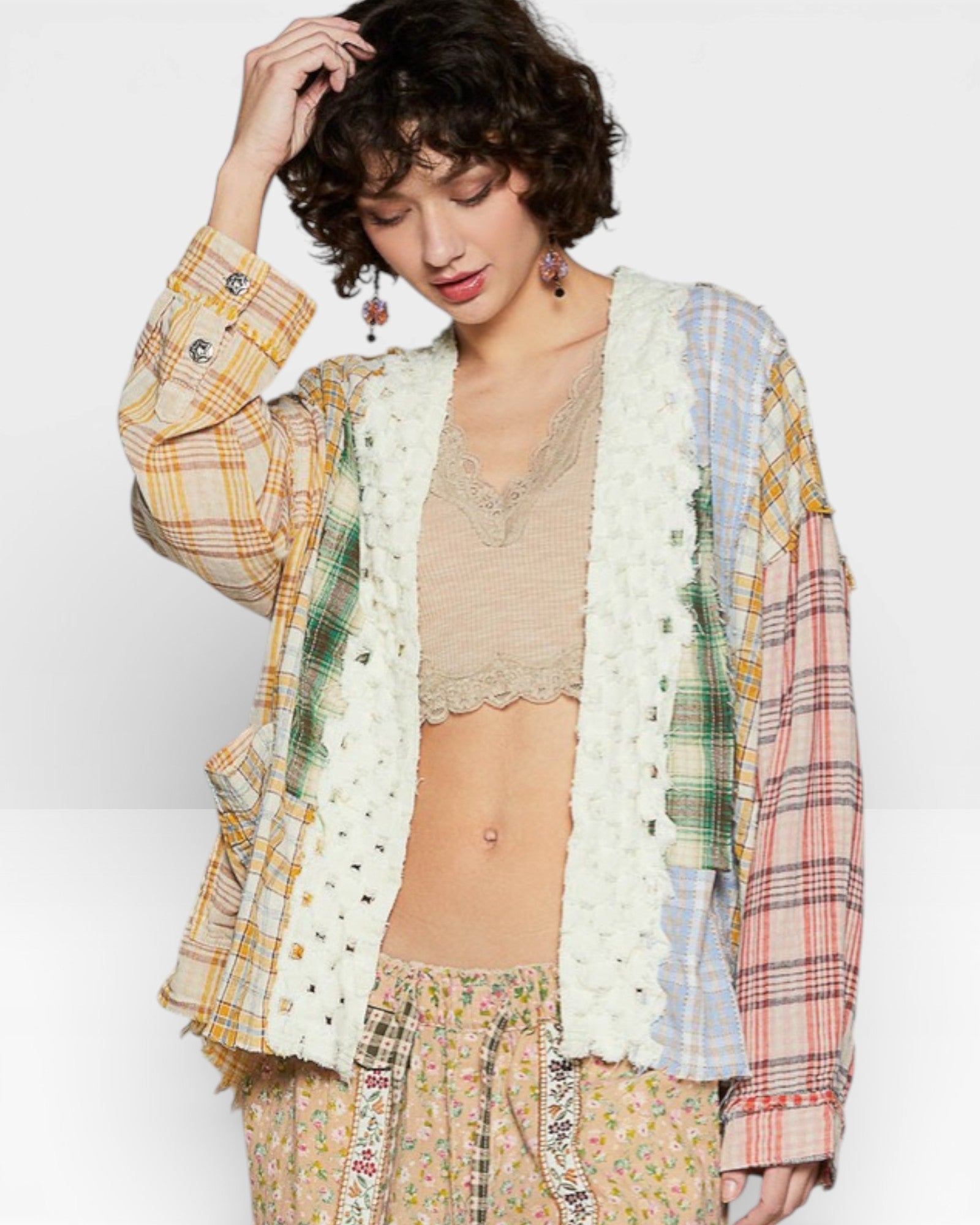 Woman wearing a plaid shirt over a lace top and floral pants on a white background