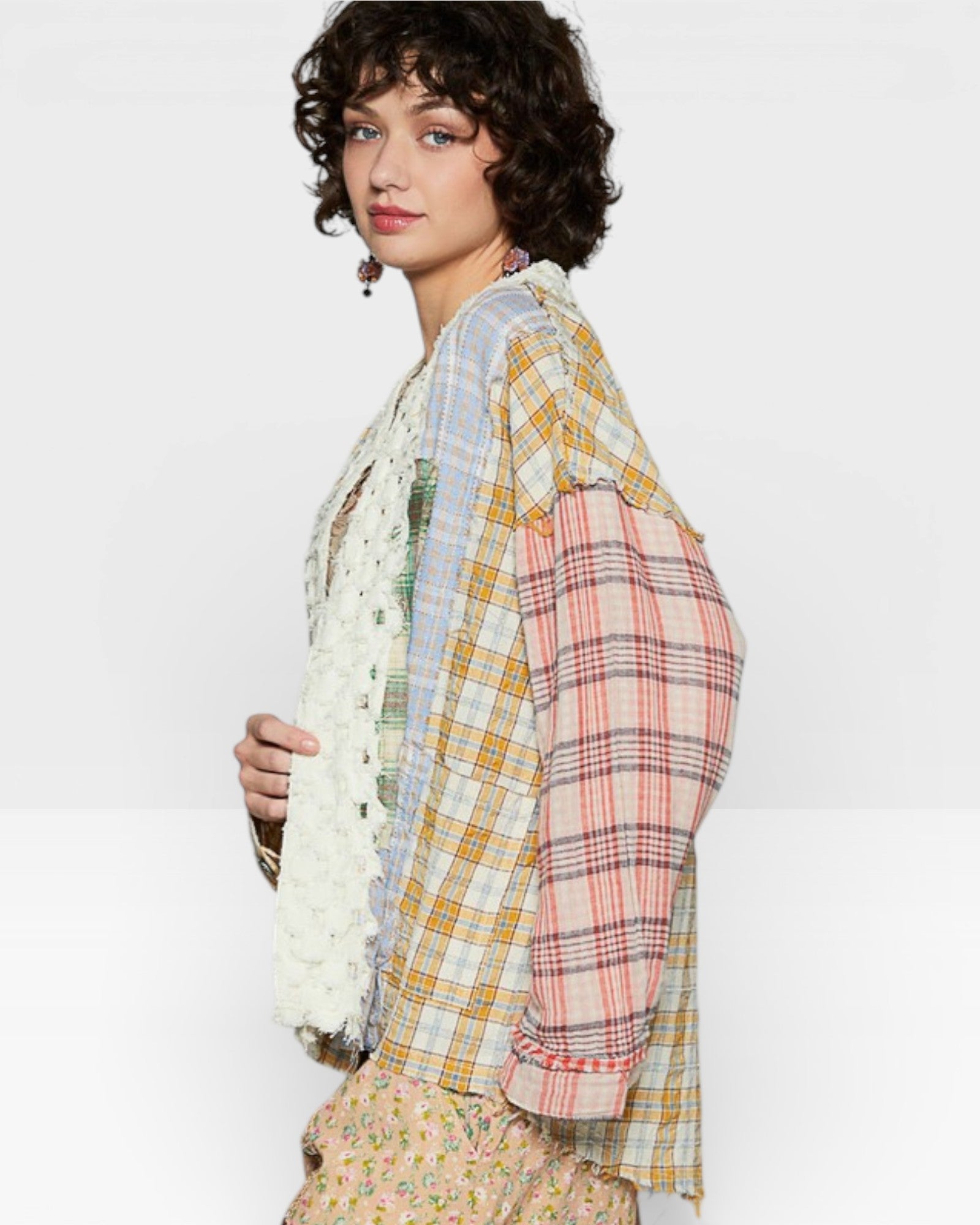 Woman wearing a colorful plaid shirt with a white scarf on a light gray background