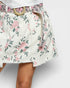 Floral patterned skirt with a belt on a plain background