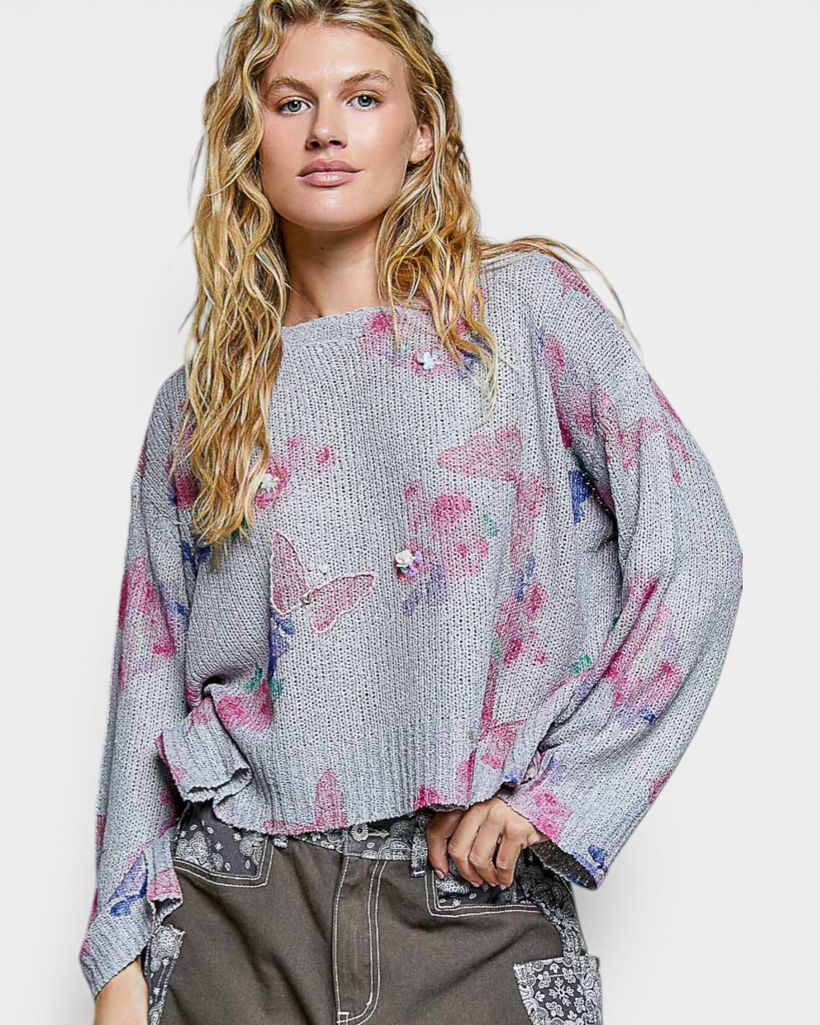 Woman wearing a gray sweater with colorful butterfly patterns on a white background