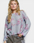 Woman wearing a gray sweater with colorful butterfly patterns on a white background