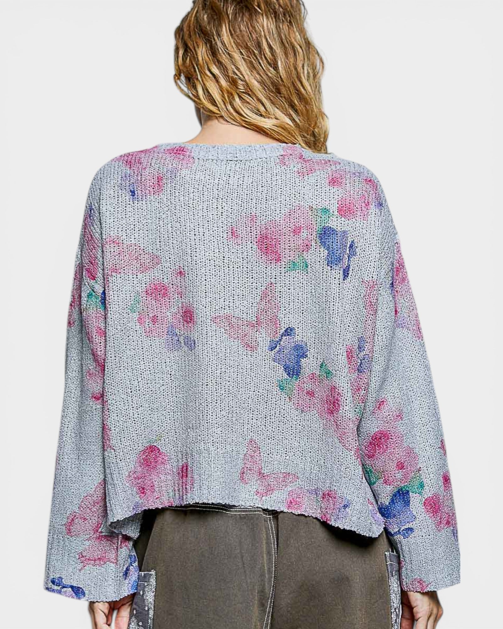 Woman wearing a gray cardigan with colorful butterfly patterns on a plain background